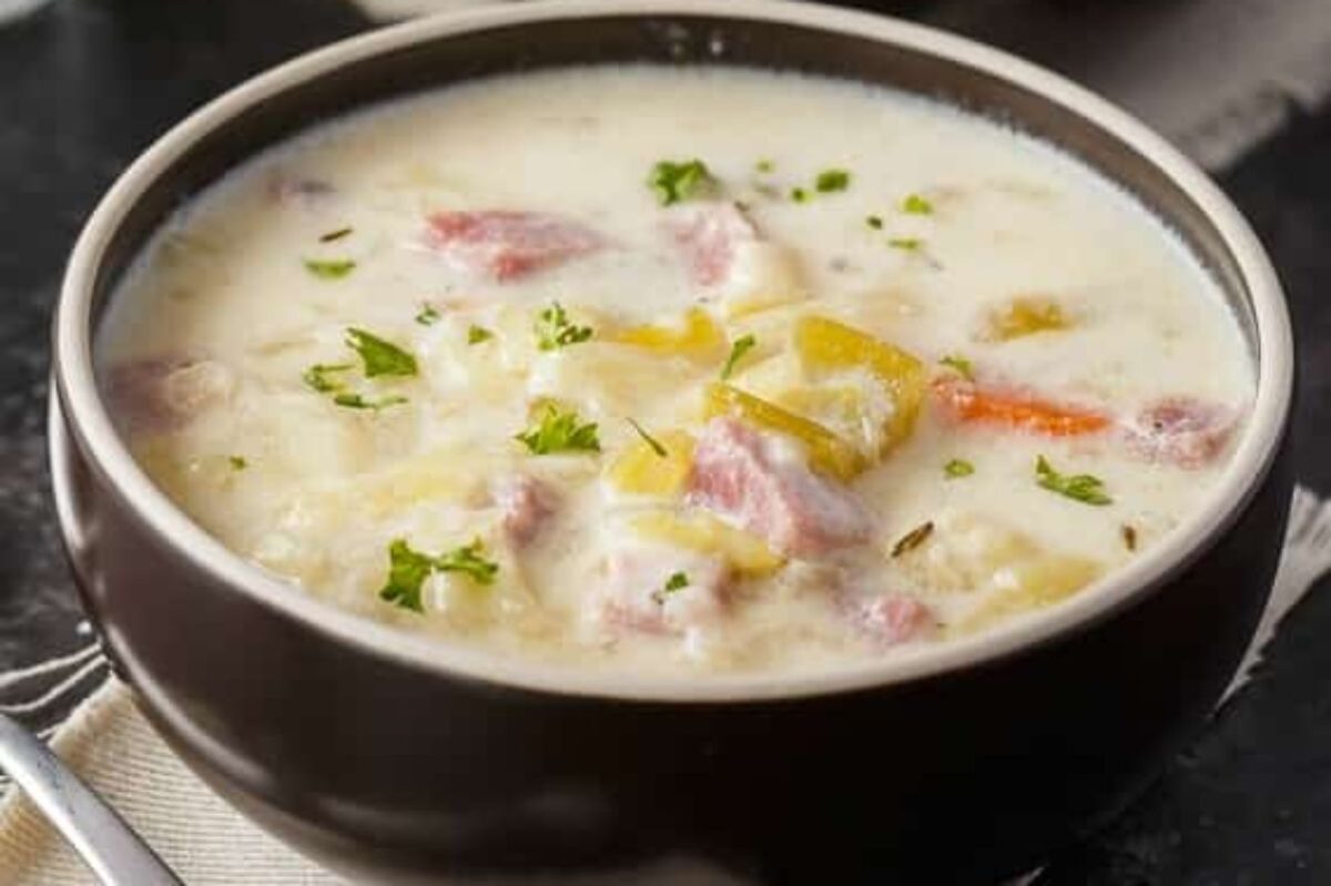A bowl of creamy soup with chunks of ham, potatoes, and carrots, garnished with parsley made from a can of cream soup.