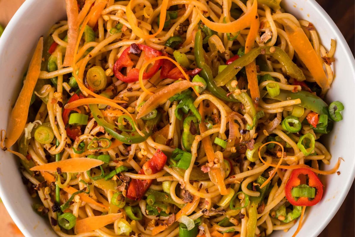 A bowl of stir-fried noodles with julienned vegetables and sliced chili peppers featuring recipes.