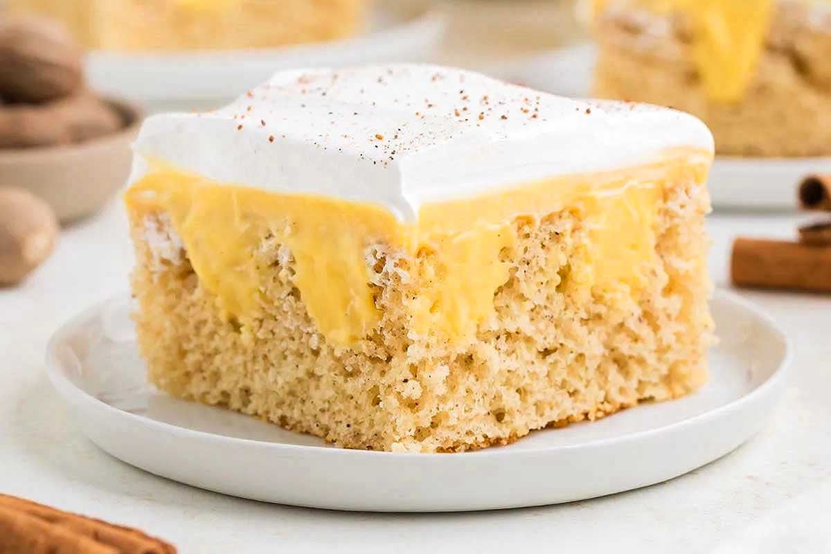 A slice of three-layer cake with a fluffy white topping and a yellow pudding mix custard filling on a white plate.