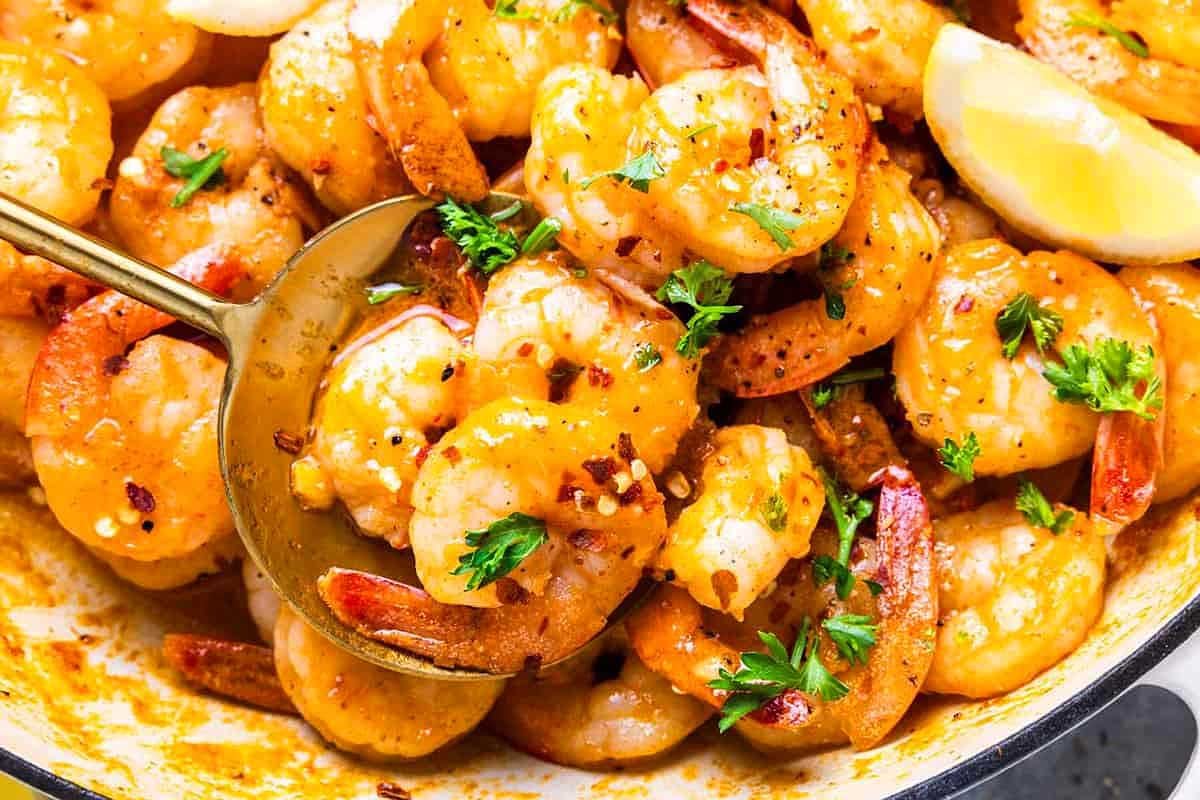 A skillet filled with saut&eacute;ed shrimp garnished with parsley and served with lemon wedges, all prepared in 30 minutes or less.