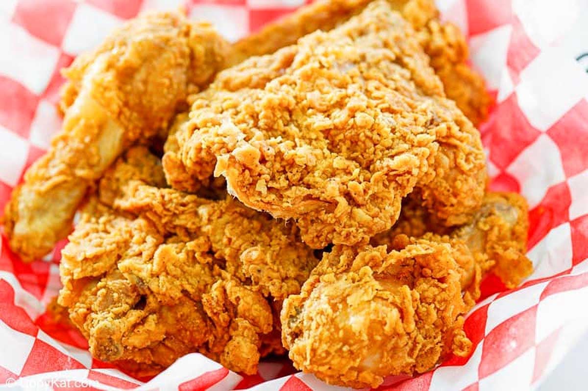A pile of crispy KFC recipe fried chicken pieces on a red and white checkered paper.
