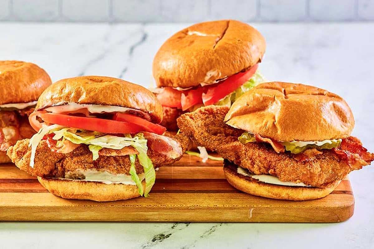 Three McDonald's recipes chicken sandwiches with lettuce and tomato on a wooden board.