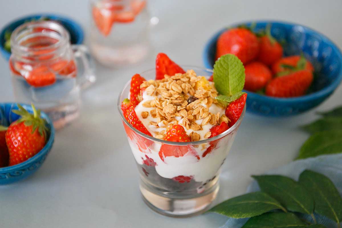 A bowl of yogurt layered with strawberries and granola, garnished with a mint leaf, inspired by McDonald's recipes.