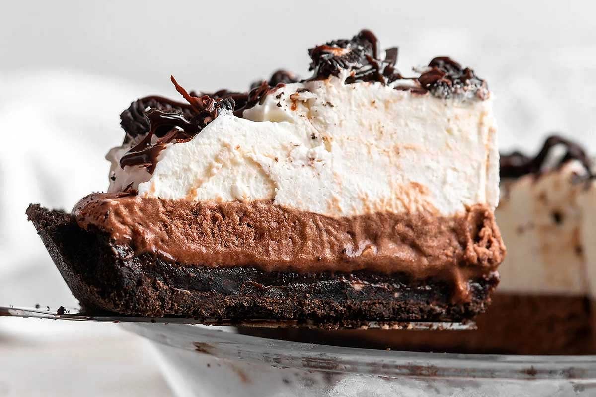 A slice of chocolate pudding mix cream pie with a cookie crumb crust on a plate.