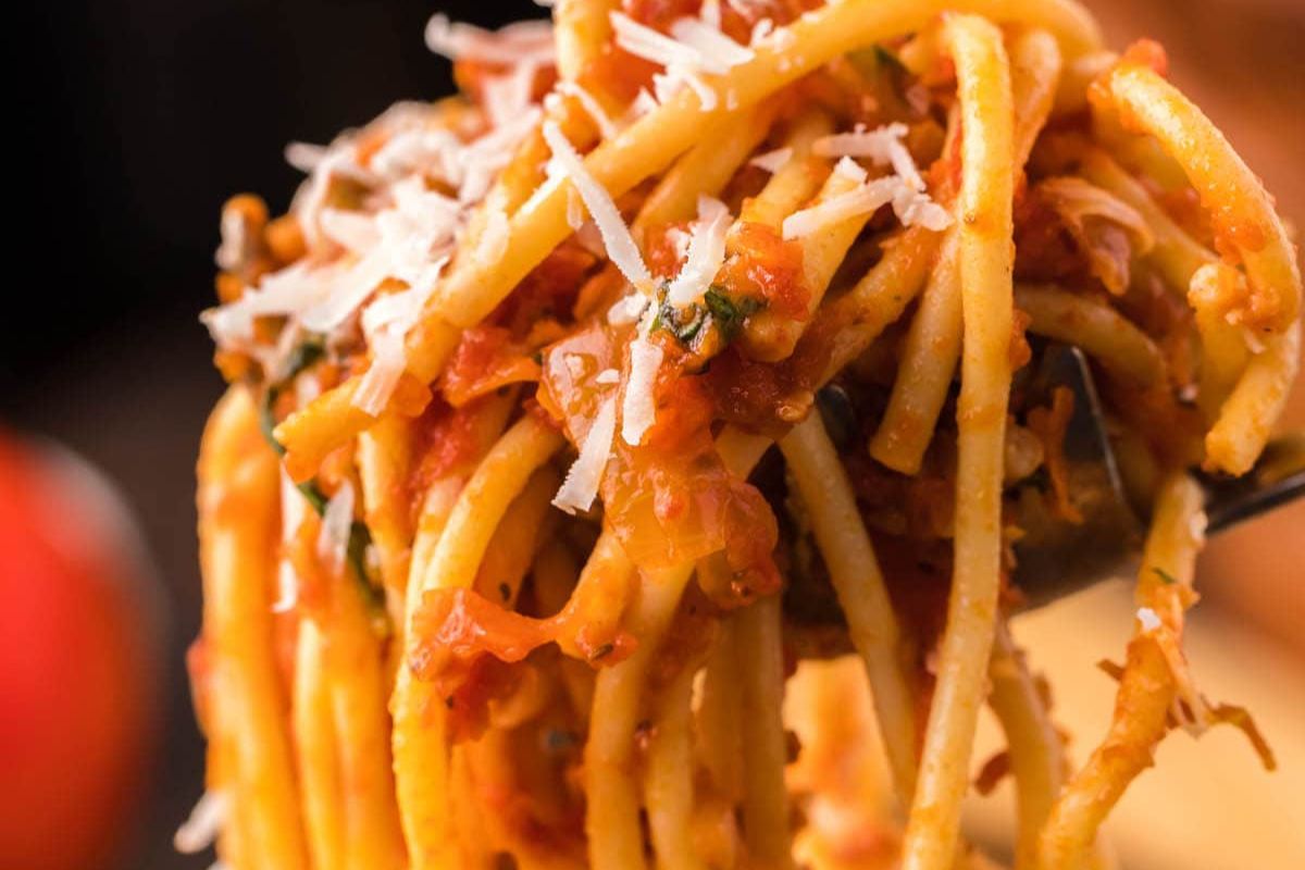 A close-up of recipes featuring noodles with tomato sauce and grated cheese on a fork.