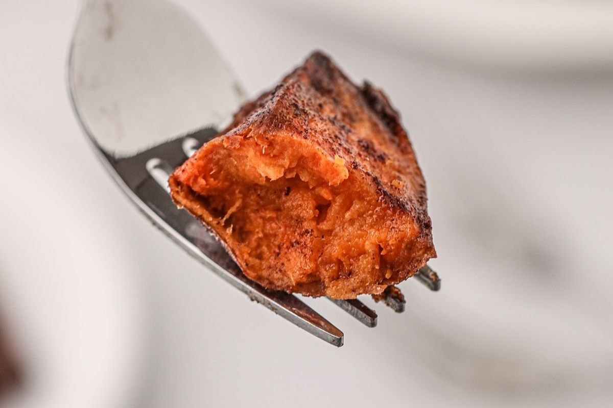 A close-up image of a piece of smoked sweet potato on a fork, highlighting its orange, moist texture.
