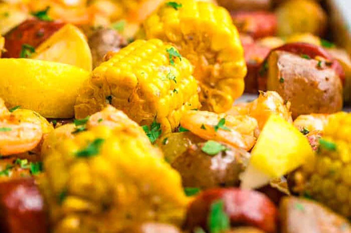 A vibrant sheet pan shrimp boil featuring shrimp, corn, sausage, and lemon wedges garnished with parsley.