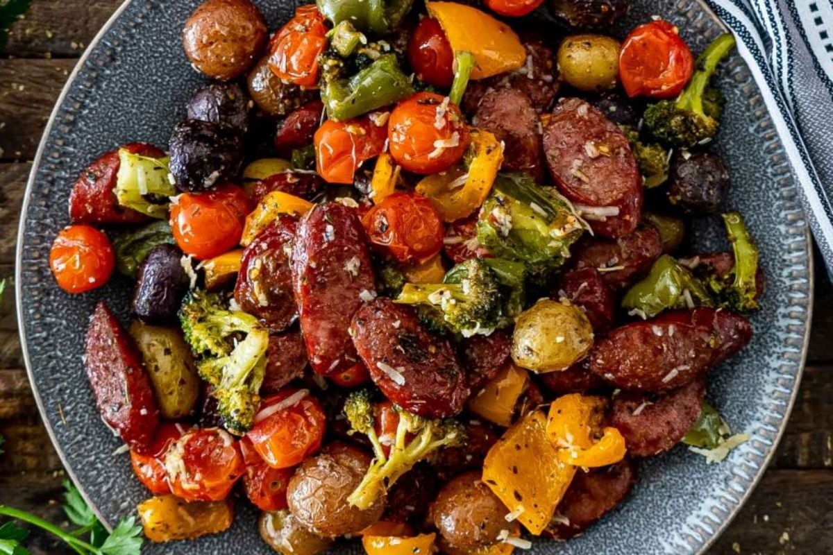 A colorful plate of roasted vegetables and sliced sausages, using frozen vegetables like broccoli, bell peppers, cherry tomatoes, and olives.