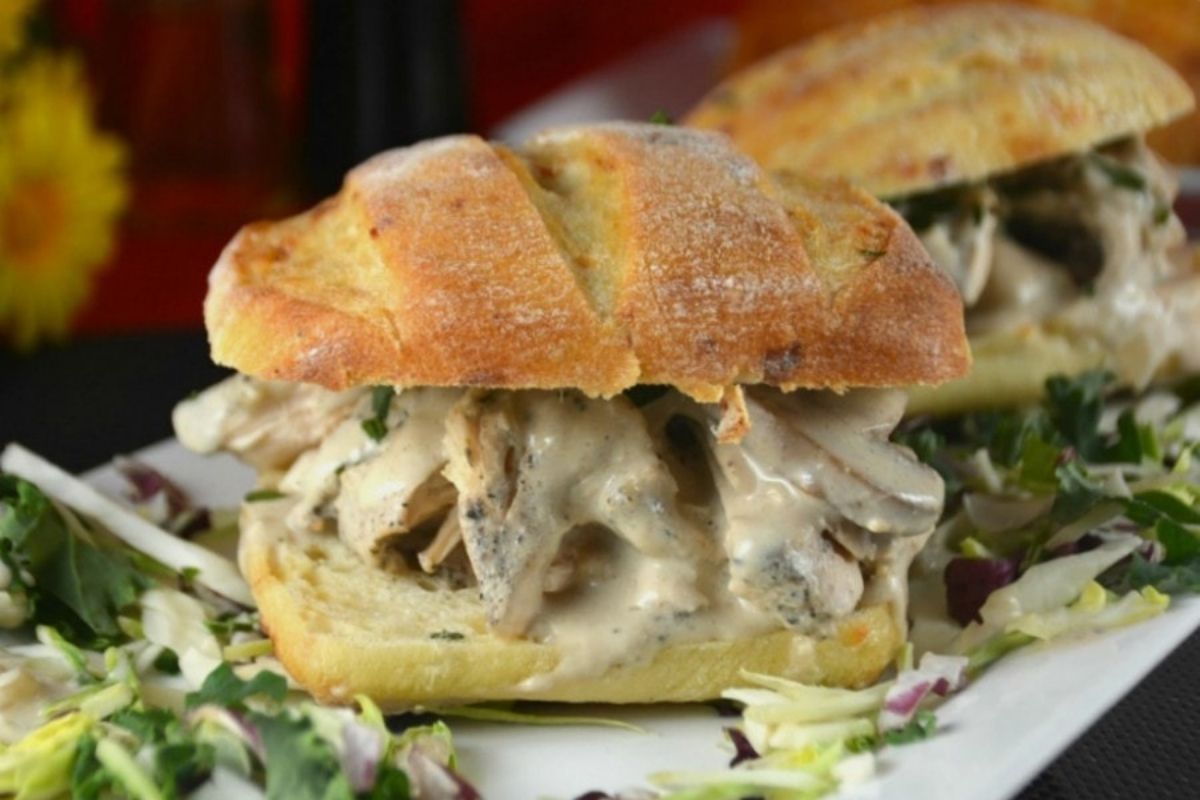 Chicken Dinners sandwich with creamy sauce on a bed of shredded lettuce.