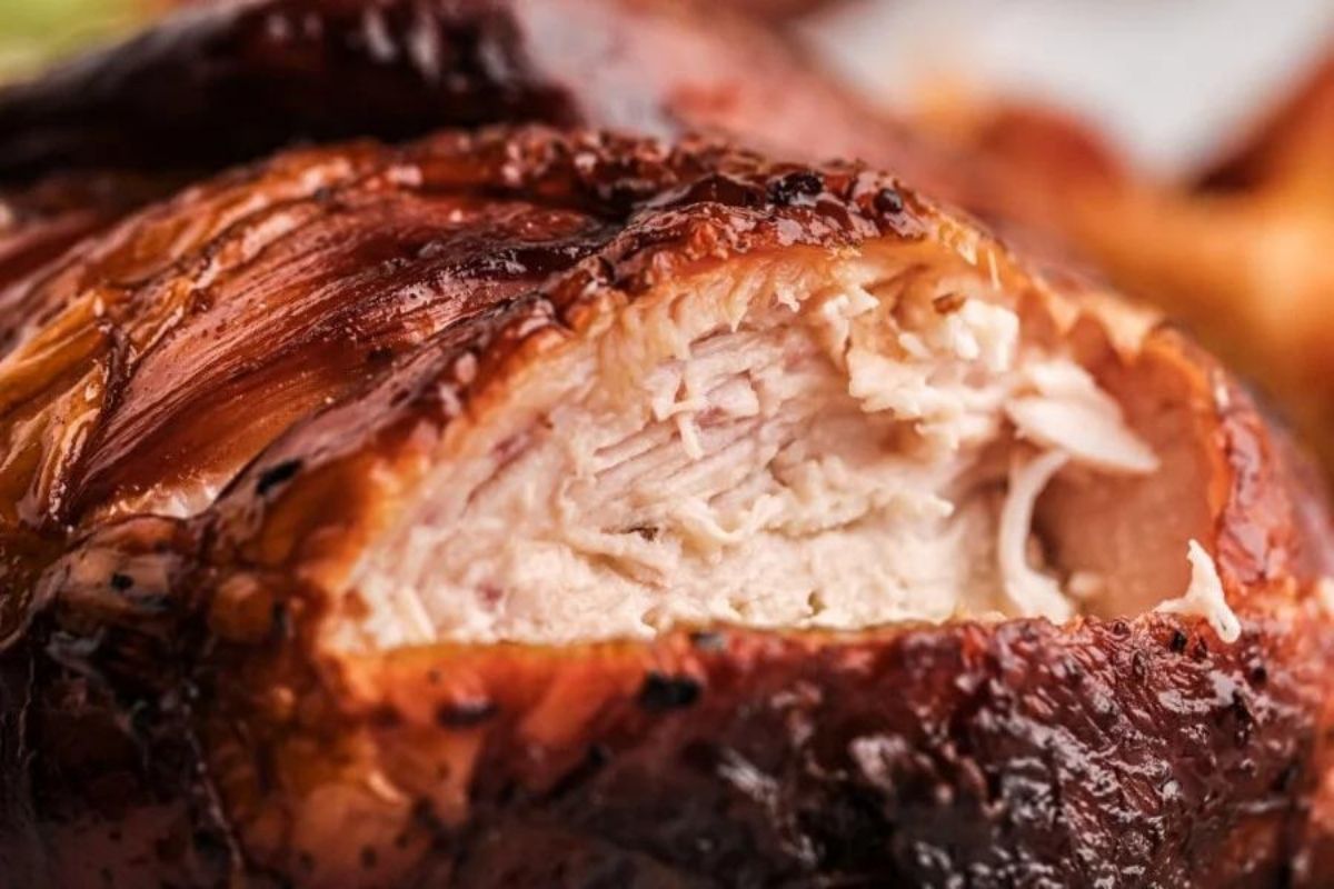 Close-up of a juicy smoked chicken thigh with crispy skin, highlighting the tender meat texture and golden-brown exterior.