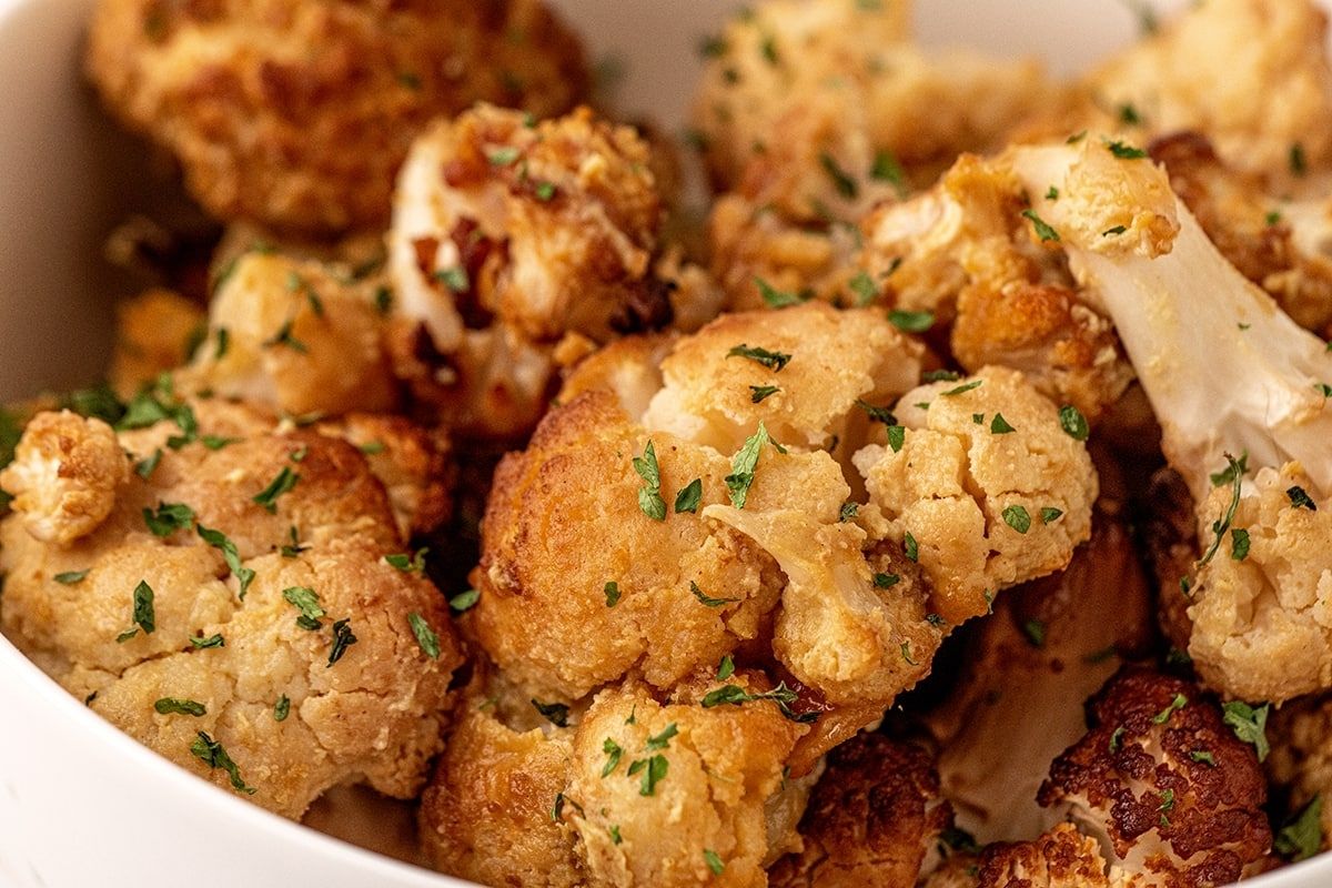 A bowl filled with roasted cauliflower florets, garnished with chopped parsley, adds a delightful twist to classic smoked recipes.