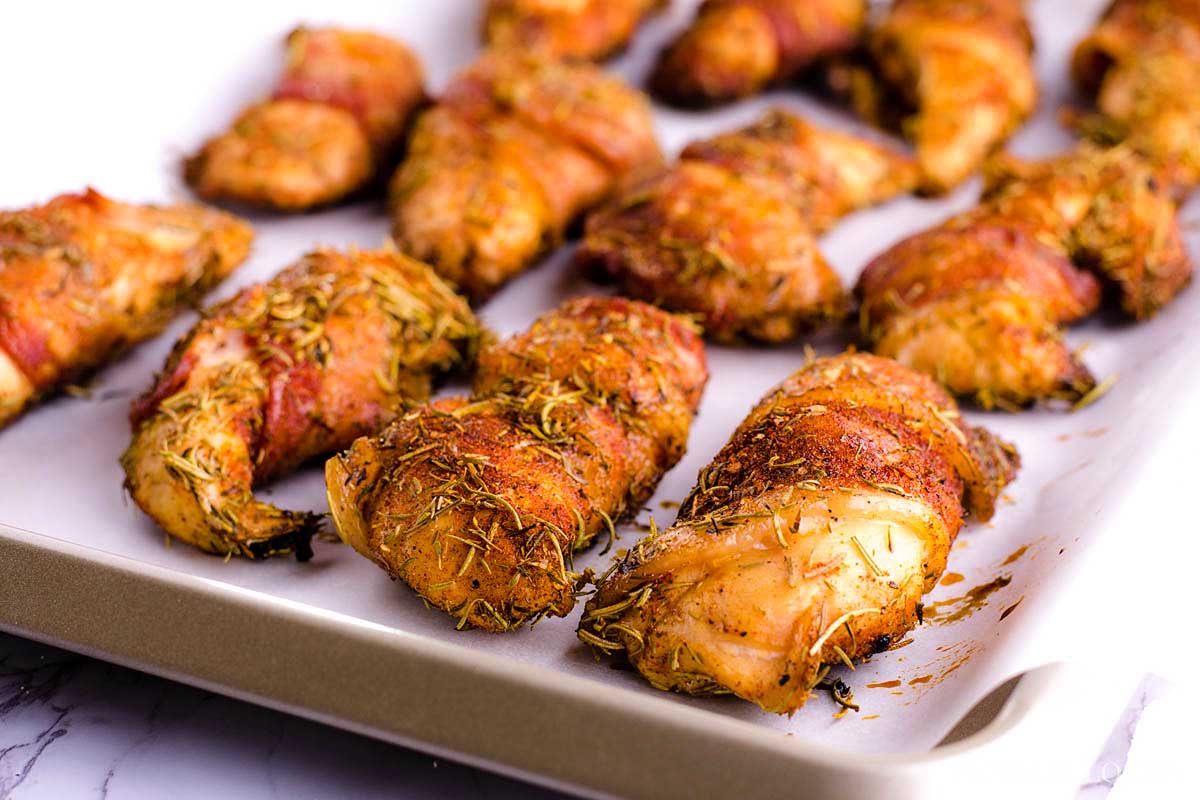 Smoked chicken drumsticks coated with herbs on a tray.