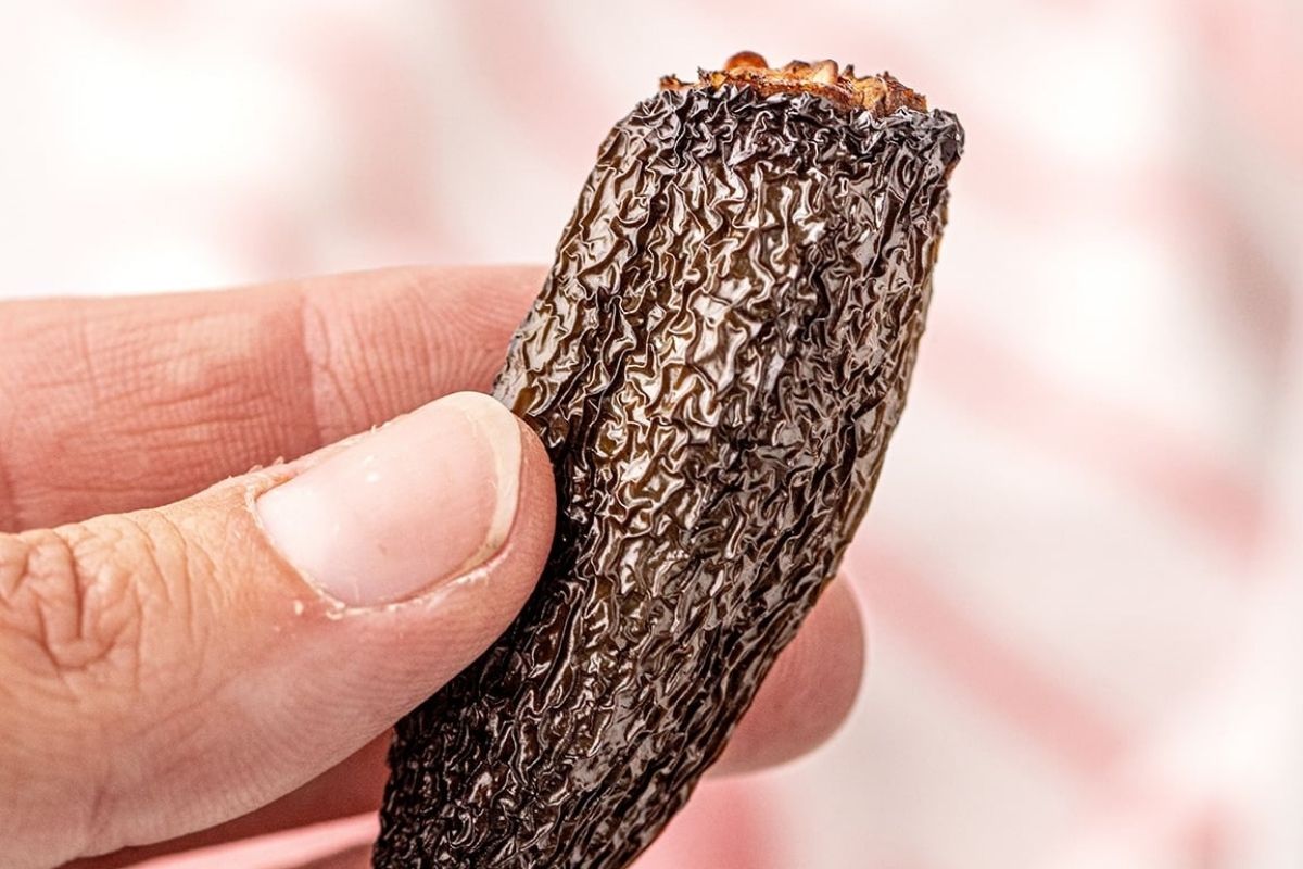 Close-up of a hand holding a half-eaten chocolate bar with a crispy, textured filling.