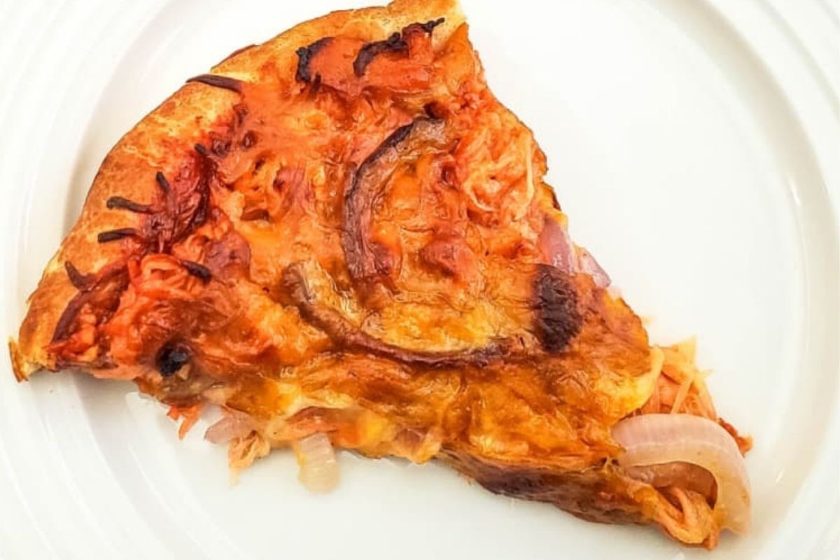 A slice of pizza with melted smoked cheese and onions on a white plate.