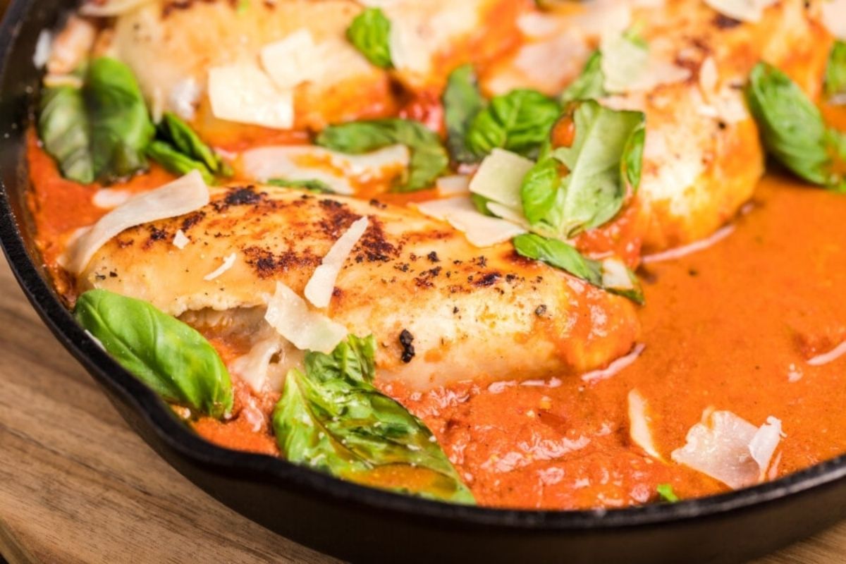Grilled chicken breast in a rich tomato sauce garnished with fresh basil, perfect for chicken dinners.