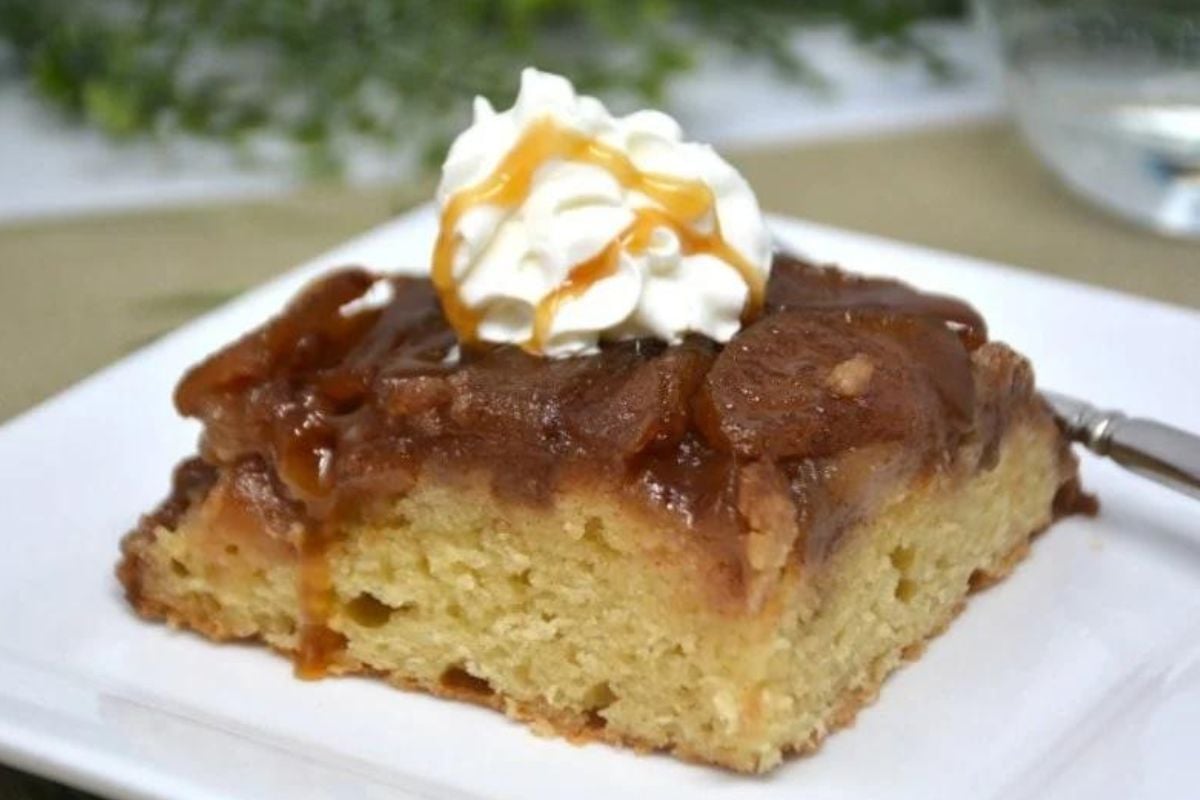 A slice of banana cake topped with caramel sauce, sourced from exquisite caramel recipes, and a dollop of whipped cream.