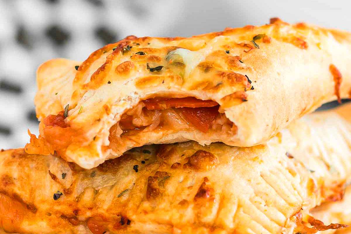 Close-up of a sliced stuffed pizza roll with visible cheese and tomato filling, garnished with herbs on top, prepared in 30 minutes or less.