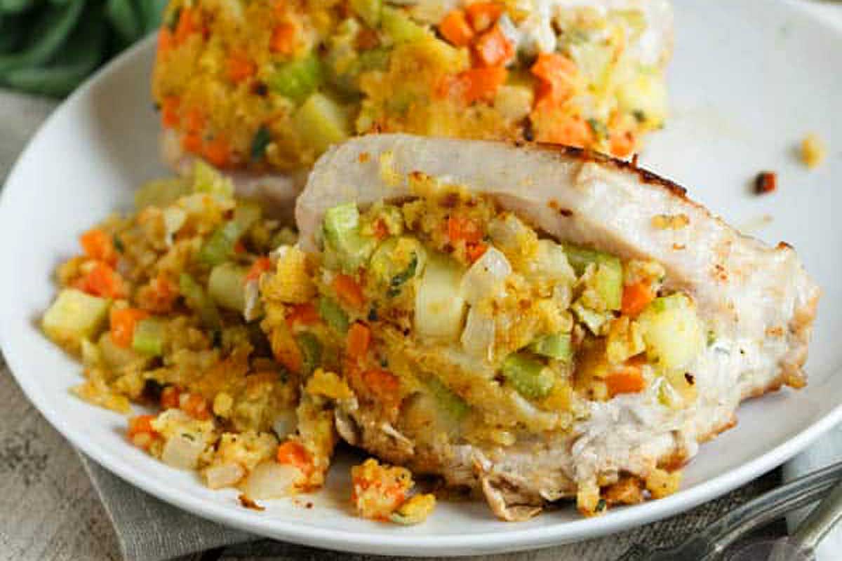 A plate of grilled pork chop with a side of colorful diced vegetable stuffing.