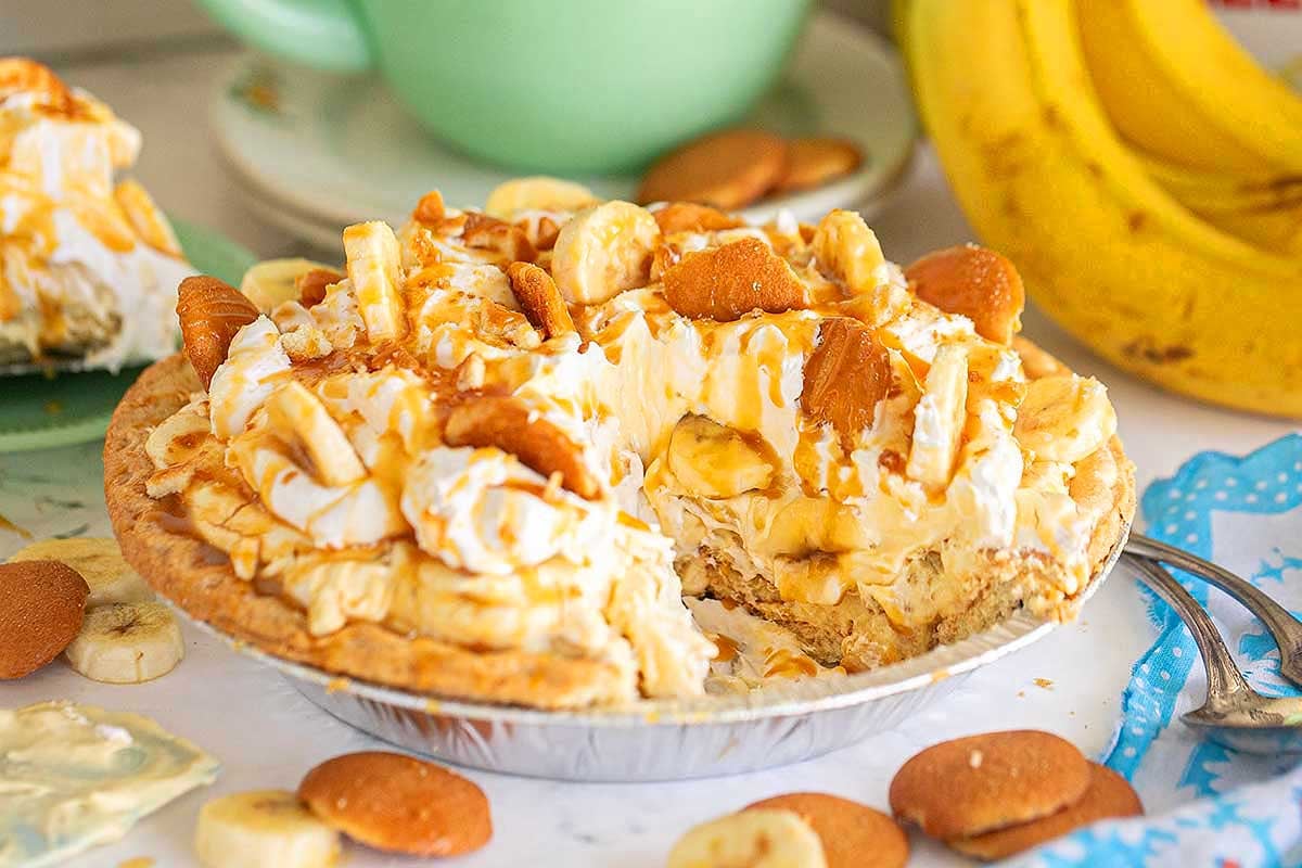 A banana cream pie made with pudding mix, topped with whipped cream, banana slices, and drizzled with caramel sauce.