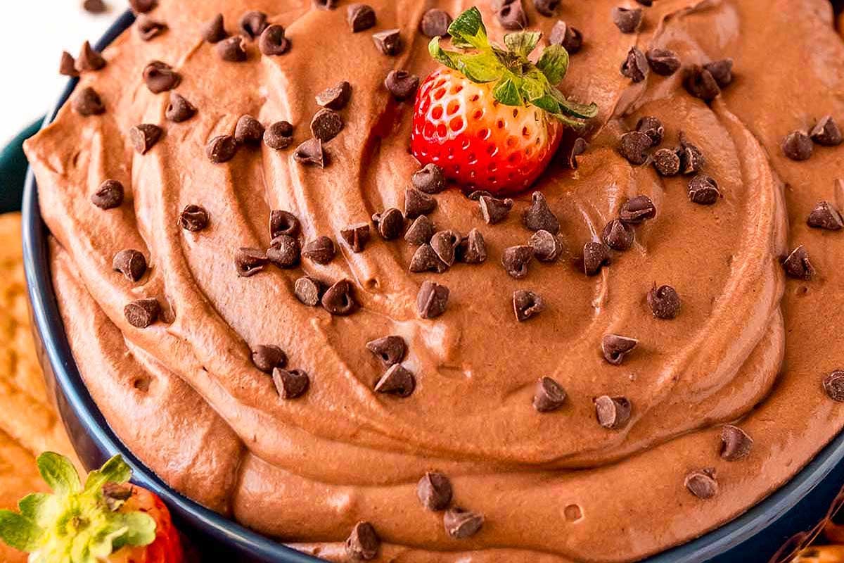 A bowl of creamy chocolate mousse made from pudding mix, garnished with a strawberry and chocolate chips.