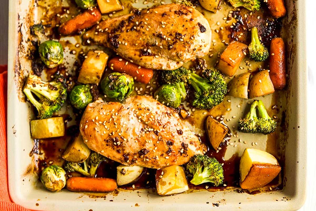 Roasted chicken breasts with carrots, broccoli, Brussels sprouts, and potatoes in a sheet pan.