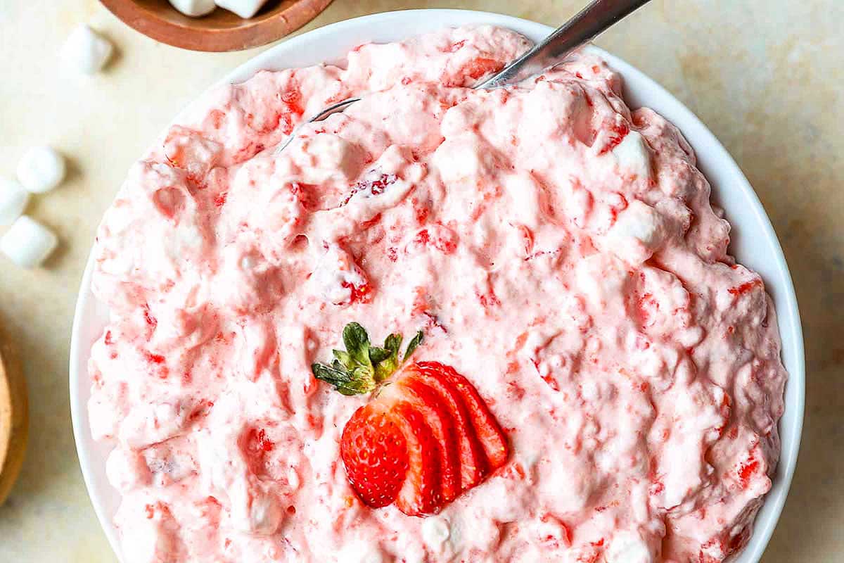 A bowl of strawberry-flavored pudding mix dessert topped with a fresh strawberry slice.
