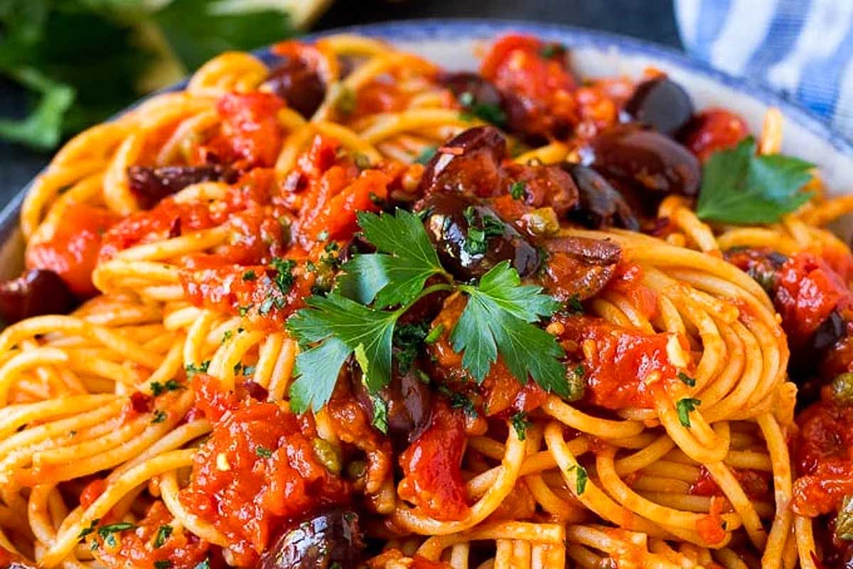 A plate of spaghetti with tomato sauce, olives, and garnished with parsley, ready in 30 minutes or less.