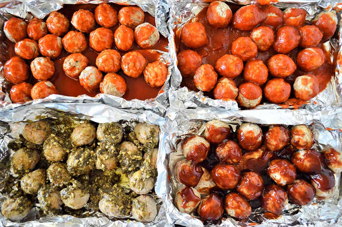 Four trays of meatballs in various sauces, displayed in sheet pan recipes containers.