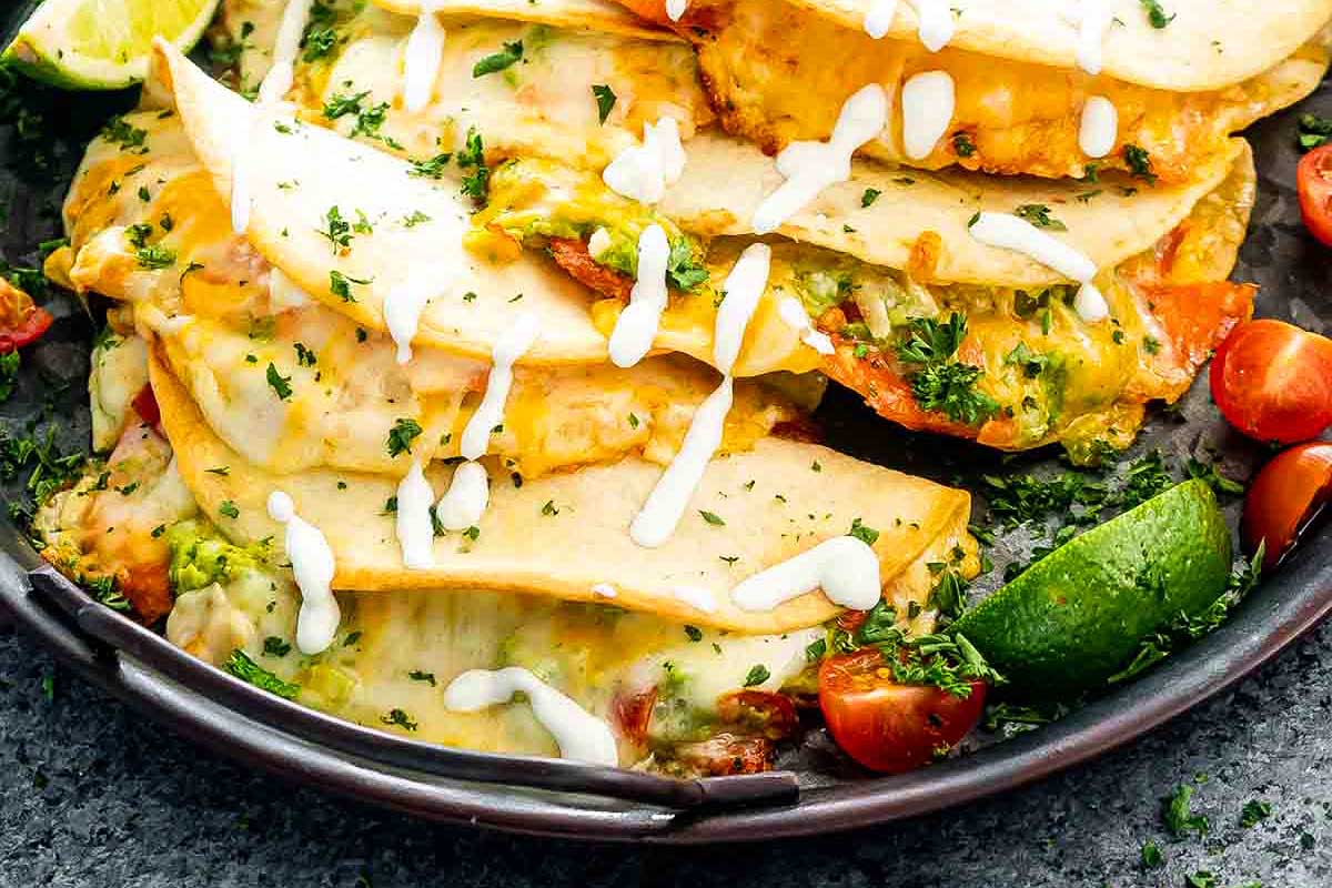 A plate of cheesy quesadillas with slices of avocado and cherry tomatoes on the side, inspired by smoker recipes.