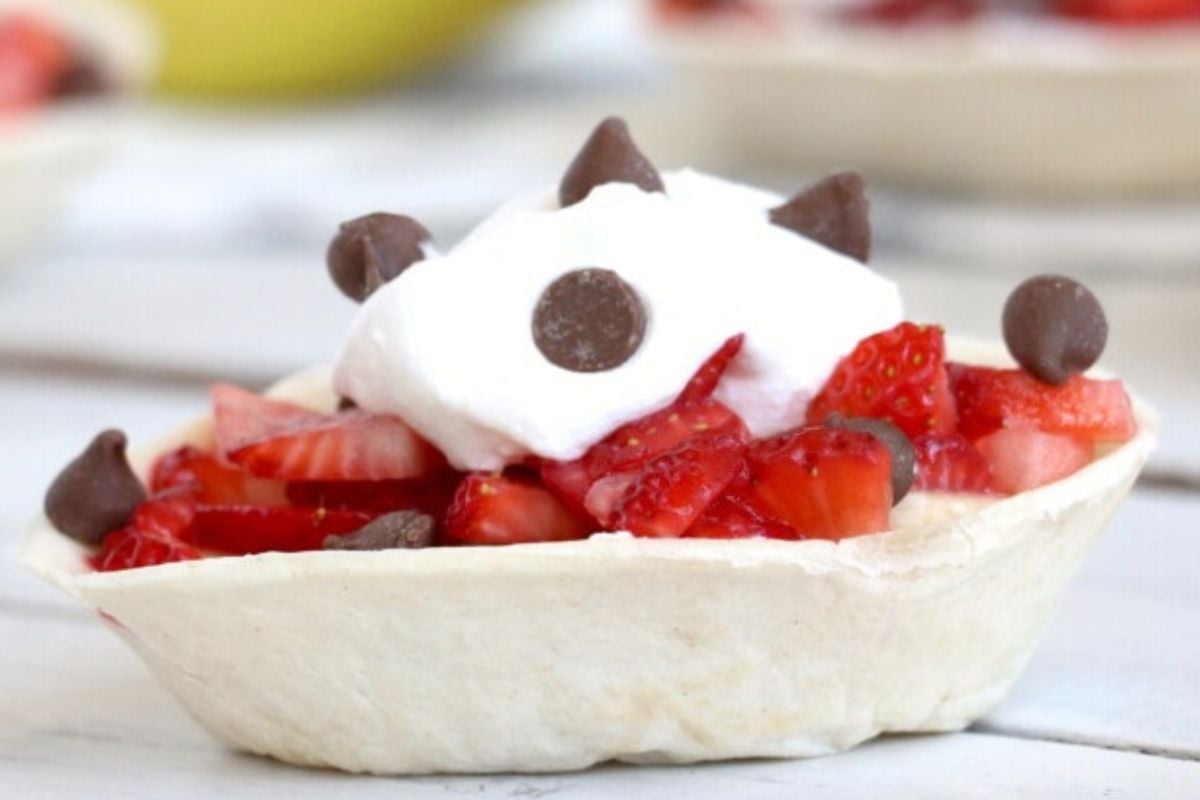 A small taco bowl filled with diced strawberries, Cool Whip, and chocolate chips.