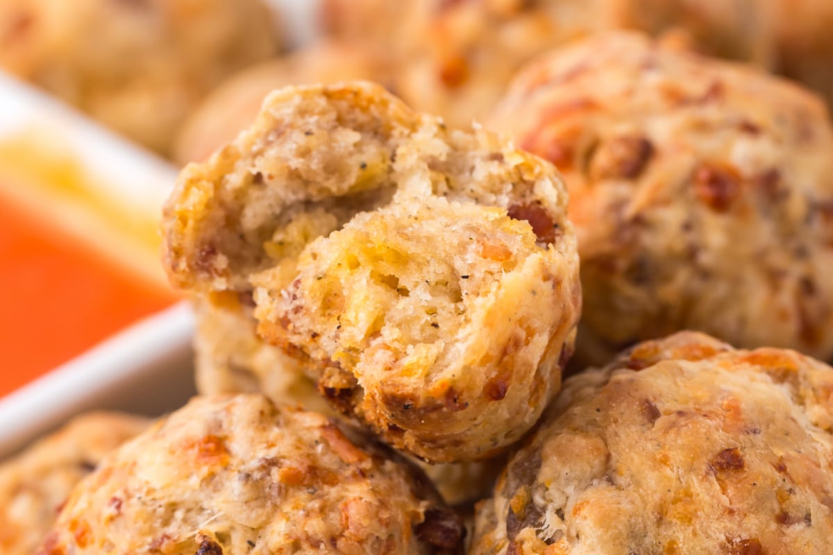 A pile of Best Bacon Sausage Balls with a bite missing from one on top.