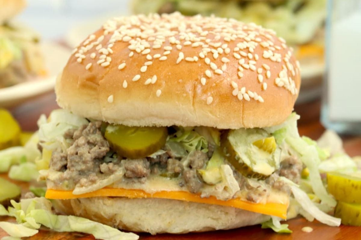 A sesame seed bun sandwich with ground beef, pickles, shredded lettuce, and a slice of cheddar cheese—perfect for fans of Big Mac inspired recipes.