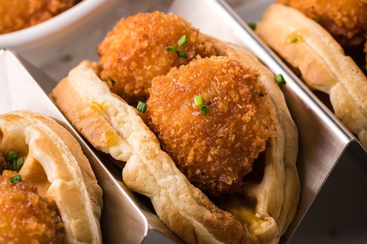 Crispy fried chicken pieces served in folded waffles, garnished with chopped chives&mdash;a delightful twist on classic chicken recipes.