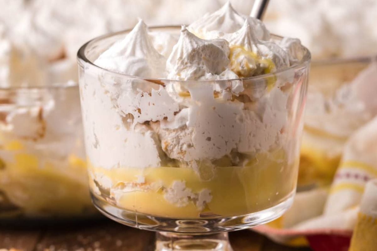 Glass dish filled with creamy lemon pudding, Cool Whip topping, and meringue, with layers visible—a delicious addition to your cool whip recipes collection.