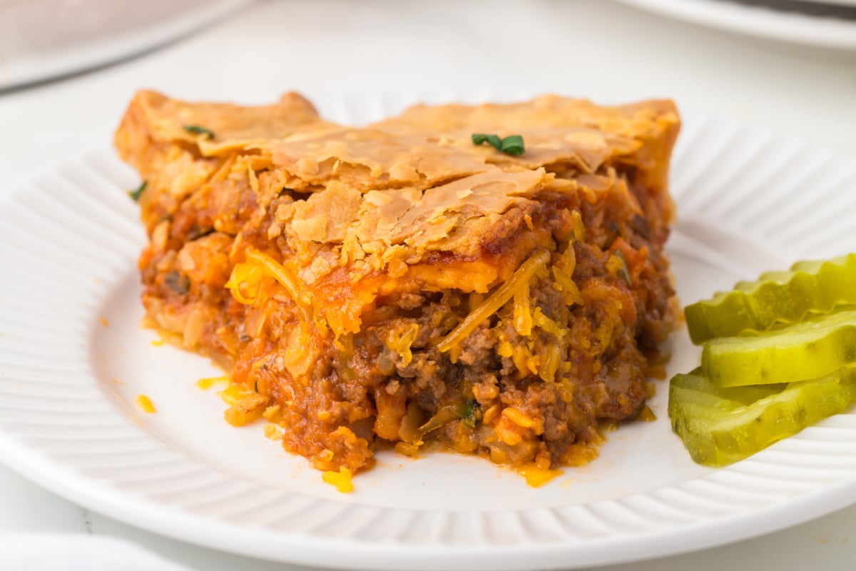 Cheeseburger Pie on a white plate missing a bite.