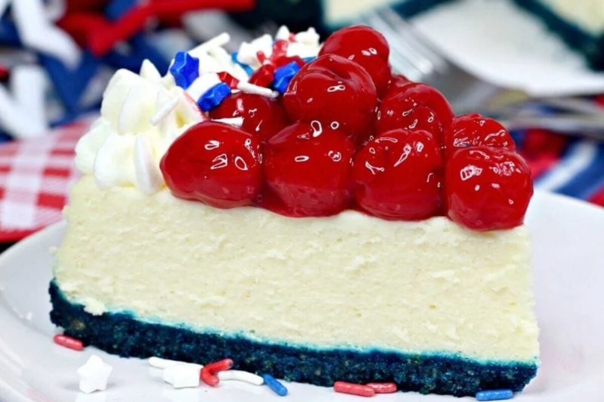 A slice of cheesecake with a blue crust, topped with a layer of cherry filling and white, red, and blue sprinkles, and whipped cream makes for one of the most patriotic desserts around.