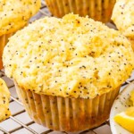 A group of lemon poppy seed muffins on a cooling rack, with fresh lemon wedges nearby, accentuating their textured tops and golden hue.