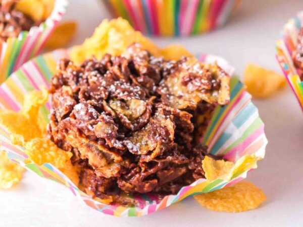 Chocolate cornflake cakes in colorful striped cupcake liners, topped with a dusting of powdered sugar.