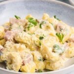 A bowl of Italian tortellini alla panna with diced ham and garnished with parsley.