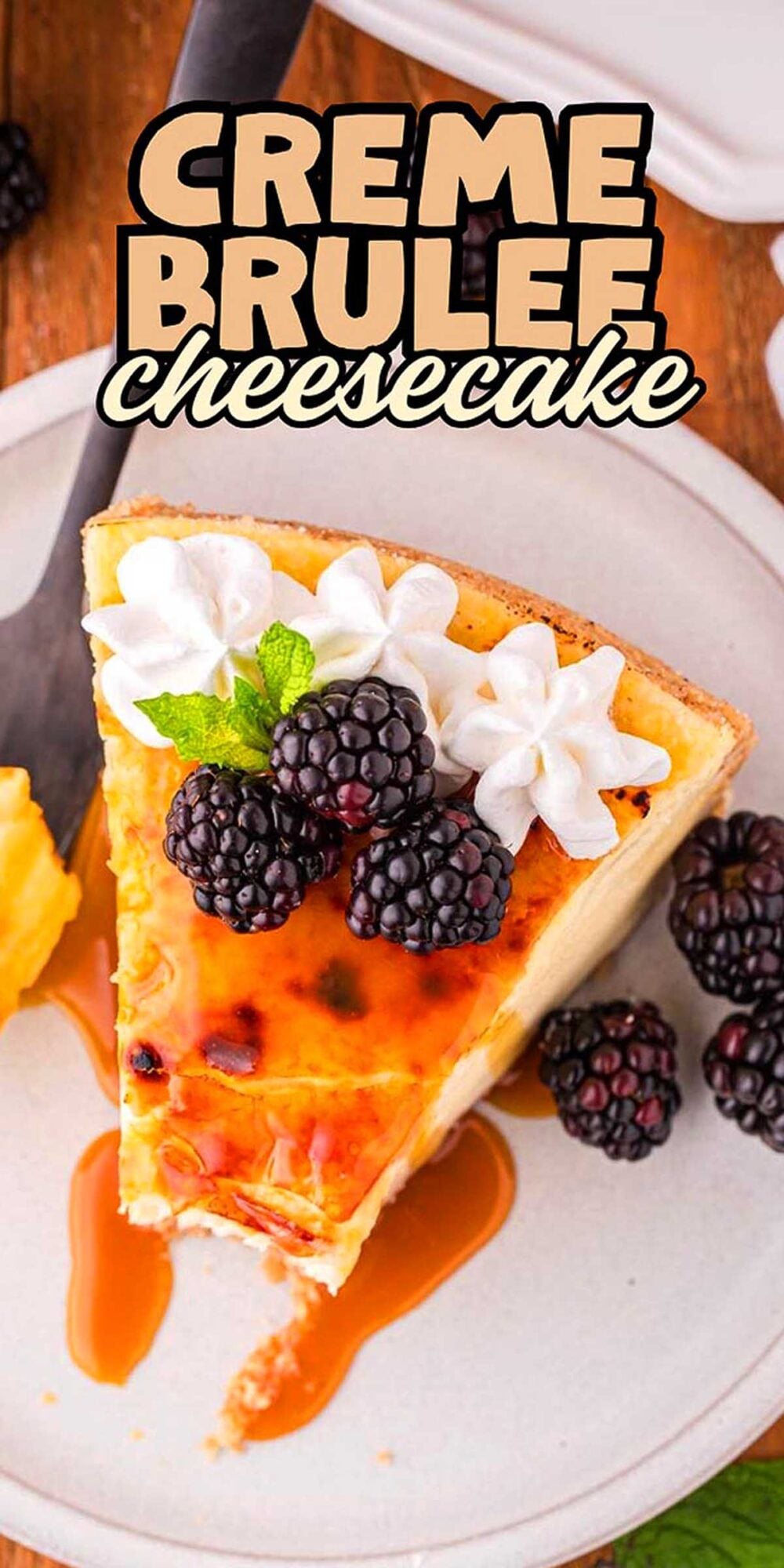 A slice of creme brulee cheesecake topped with whipped cream, blackberries, and mint on a plate.