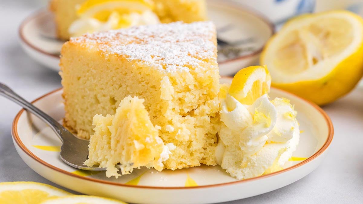 Moist lemon ricotta cake topped with powdered sugar and lemon slices.