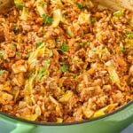 A green pot filled with deconstructed cabbage rolls—a cooked dish containing ground meat, shredded cabbage, rice, and herbs.