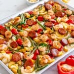 A Sheet Pan Shrimp and Andouille Sausage dinner with bell peppers, onions, and sliced squash, garnished with herbs.