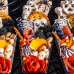 Three Mini Halloween Charcuterie Boards featuring crackers, meats, cheeses, nuts, blackberries, pretzels, and miniature candy skeletons.