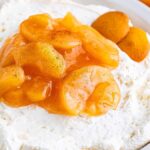 A dish of apple pie cheesecake dip topped with spiced apple slices, accompanied by vanilla wafers and waffle cookies on the side.