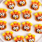 A plate of Rolo pretzel turkeys made of pretzels, candy corn, and chocolate, arranged in neat rows.