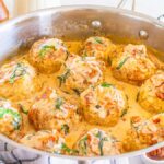 A skillet with marry me chicken meatballs in creamy sauce, garnished with fresh herbs.