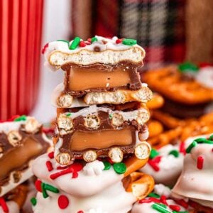 Stacked Christmas Rolo pretzel sandwiches with a white chocolate coating, caramel filling, and red and green sprinkles.