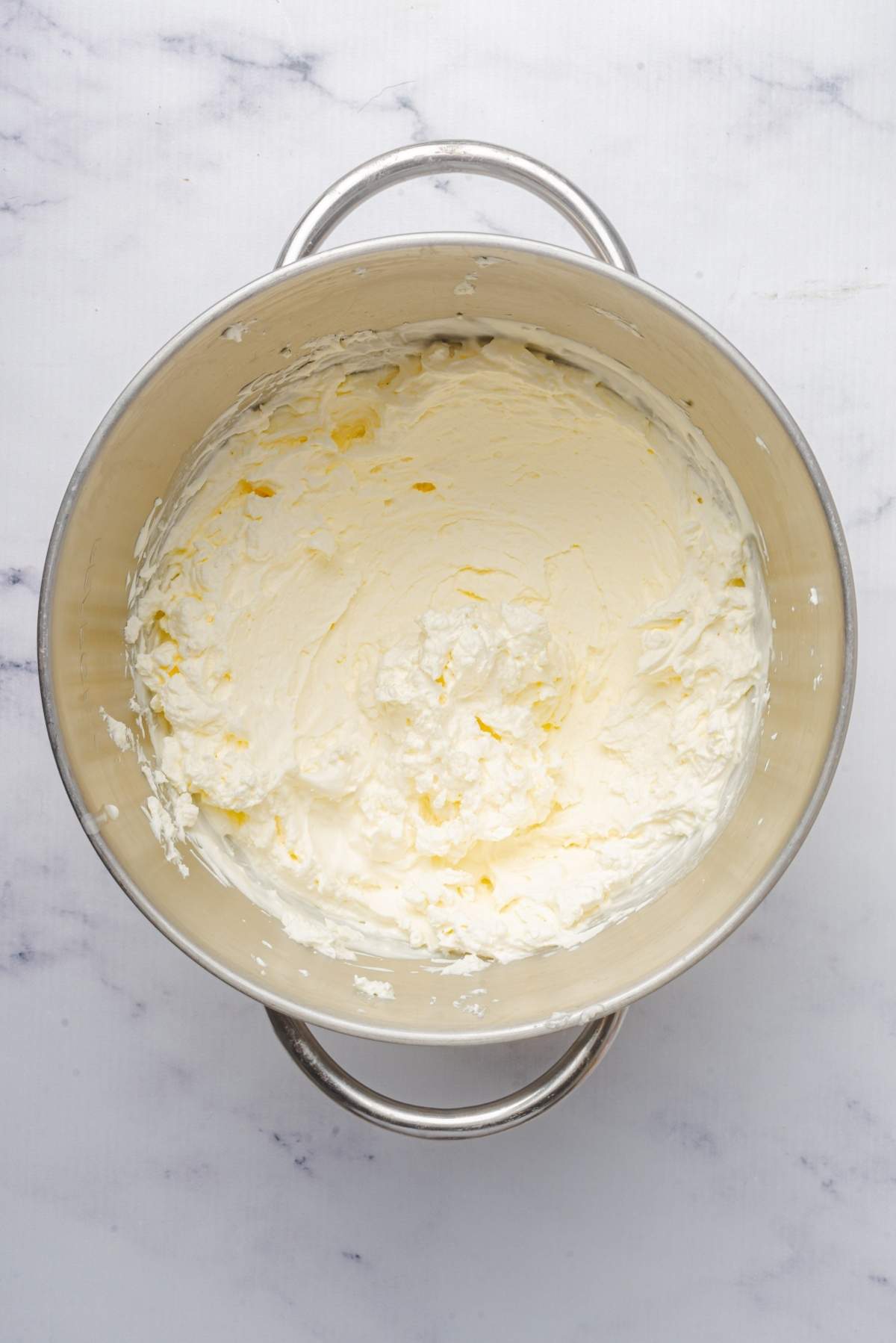 A bowl filled with fluffy whipped cream, perfect for pairing with homemade no churn cookie dough ice cream.