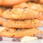 A stack of three potato chip cookies with chocolate chips and chunks, surrounded by scattered chocolate pieces.